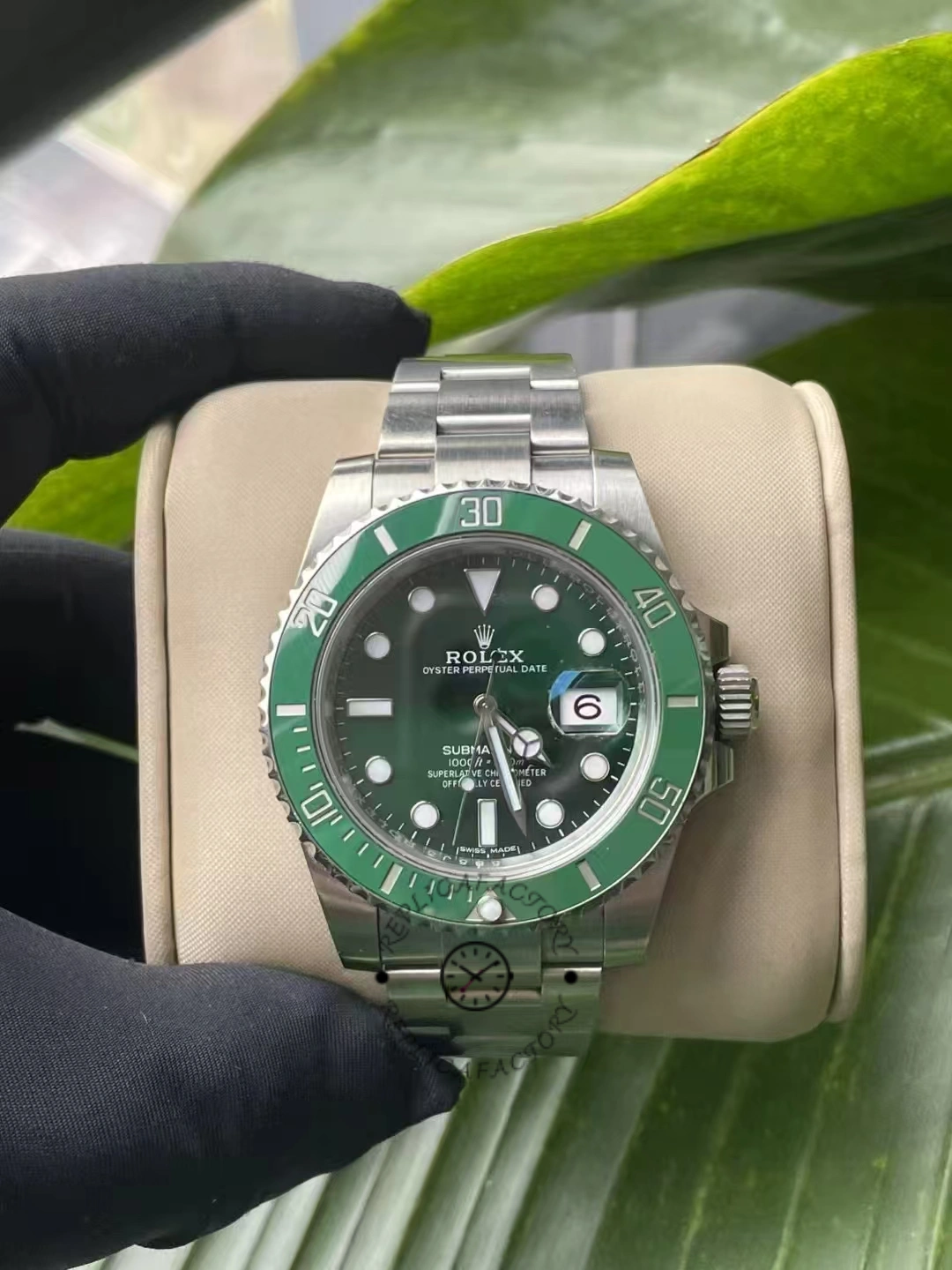 Front view of Rolex Submariner Date 116610LV with green dial and bezel, displayed on beige cushion.