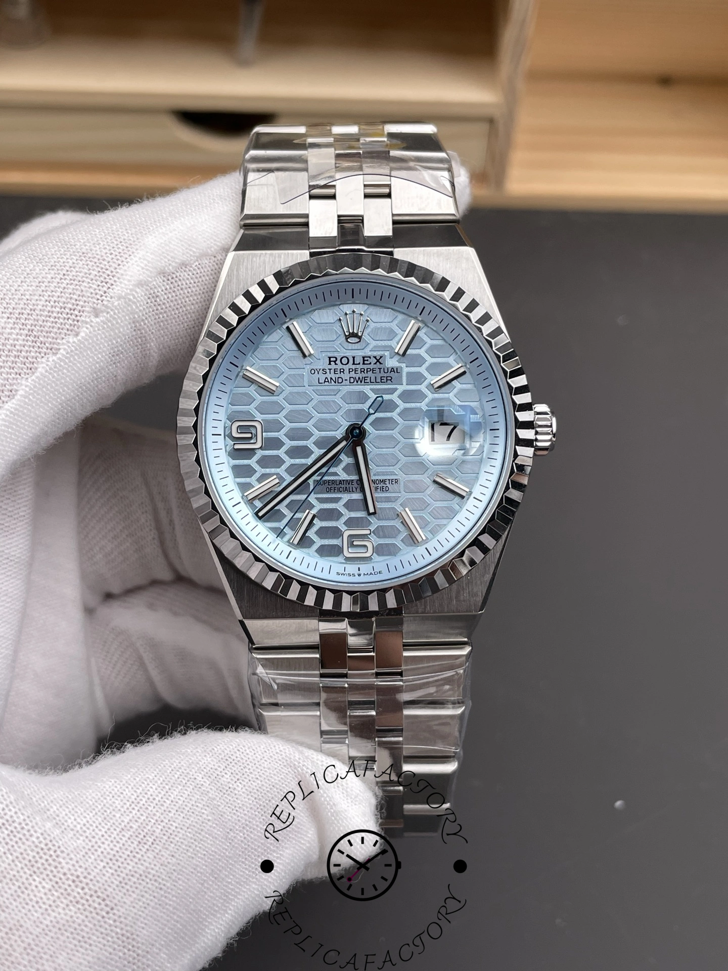 Handheld front angle of Rolex Land-Dweller 40 127336-0001 Replica showing ice blue dial texture and fluted bezel.