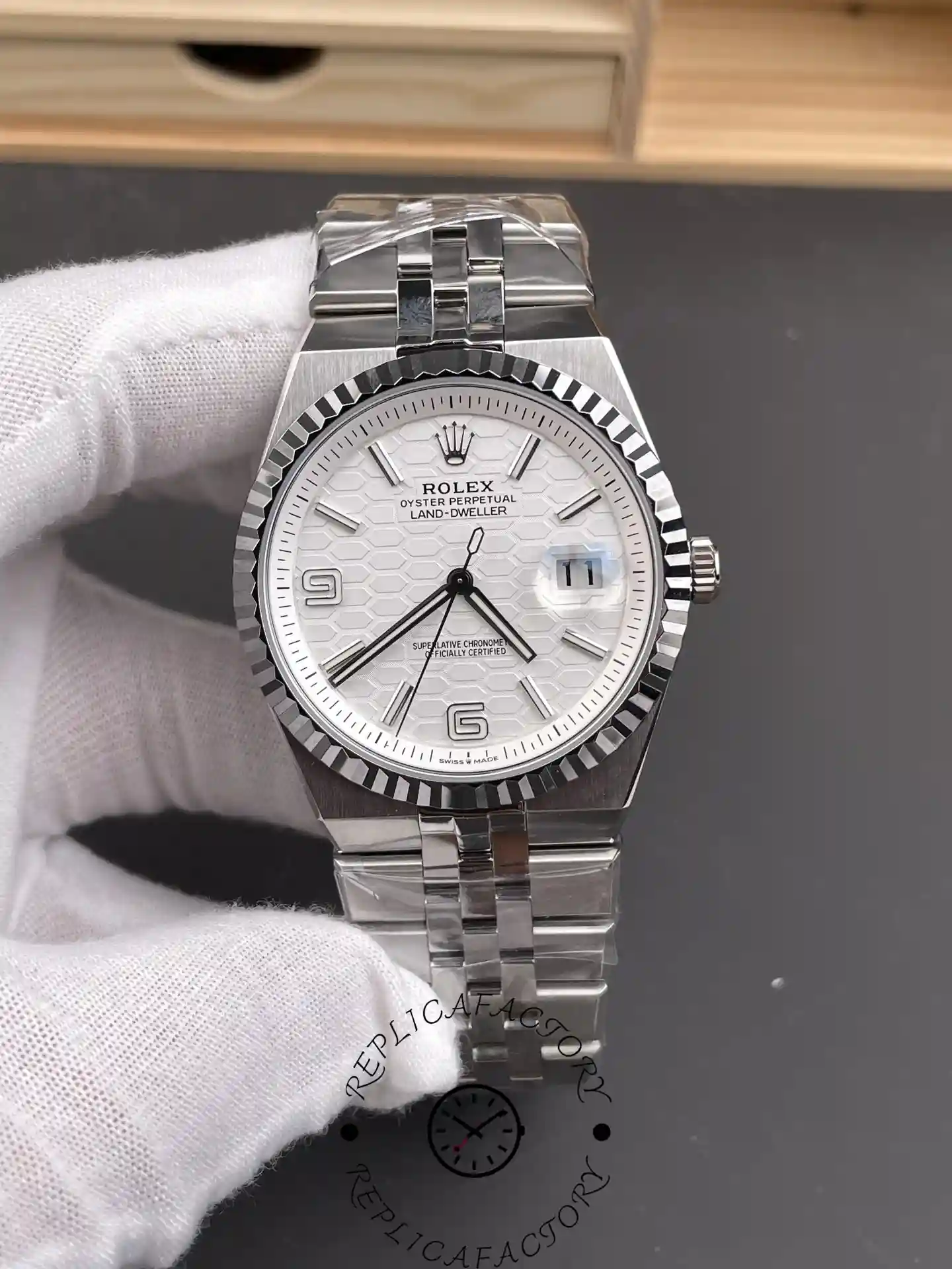 Handheld front angle of Rolex Land-Dweller 40 M127334-0001 Replica showing dial texture, cyclops date and fluted bezel.